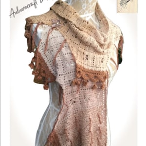 May include: A crocheted scarf in shades of brown and beige with a fringe border. The scarf is draped over a white mannequin.