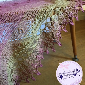 A delicate shawl featuring dragonflies and a intricate lace edge. Draped across a small coffee table.