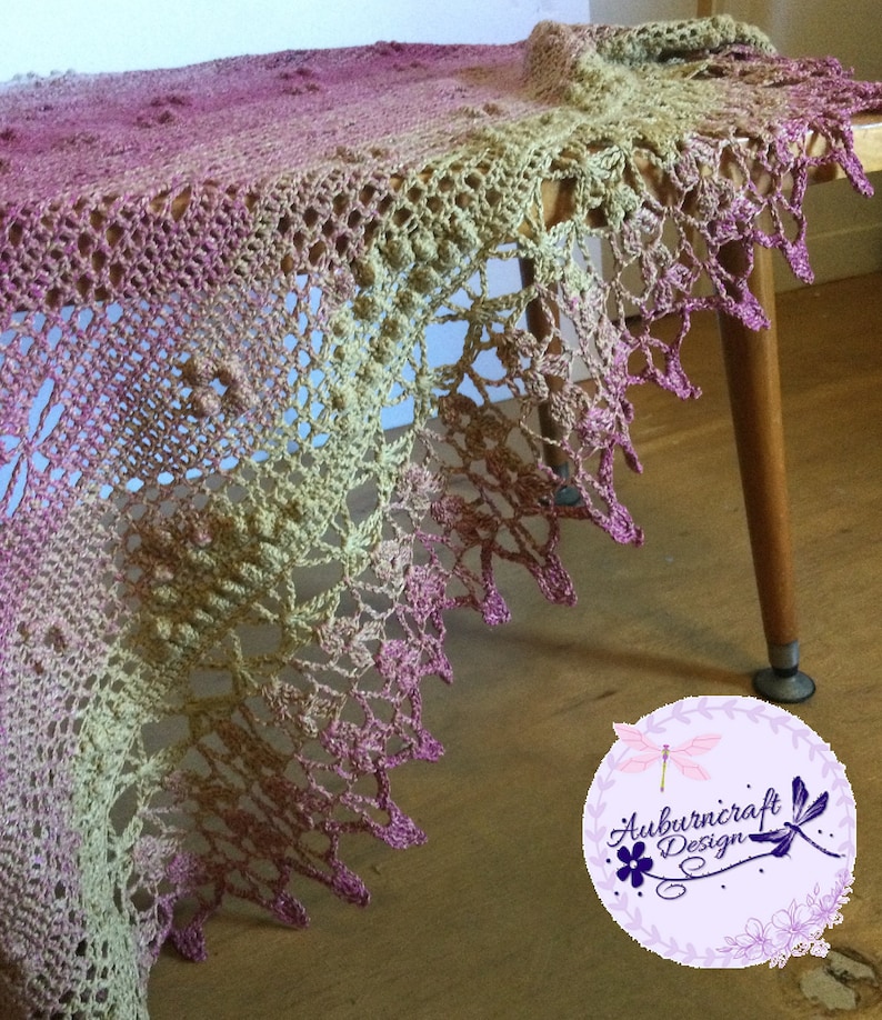 A delicate shawl featuring dragonflies and a intricate lace edge. Draped across a small coffee table.