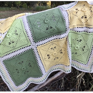 May include: A crocheted blanket with a square pattern featuring a dragonfly design. The blanket is made in shades of green, yellow, and white.