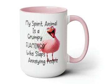 May include: White ceramic mug with a pink rim and handle. The mug features a cartoon flamingo with the text "My Spirit Animal Is a Grumpy Flamingo Who Slaps Annoying People".