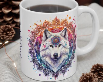 May include: White ceramic mug featuring a detailed illustration of a wolf's face within a colorful mandala design. The mug has a curved handle and is filled with a dark liquid. The design includes shades of purple, blue, orange, and pink.