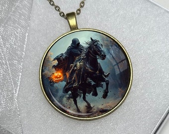 May include: A round pendant necklace with a bronze chain. The pendant features a spooky image of a headless horseman riding a black horse, carrying a jack-o'-lantern. The pendant is 40mm in diameter and is displayed in a white box.