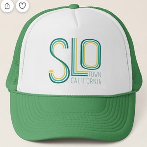 May include: A white and green trucker hat with a retro-style graphic of the text "SLO TOWN CALIFORNIA" in yellow, blue, and green.