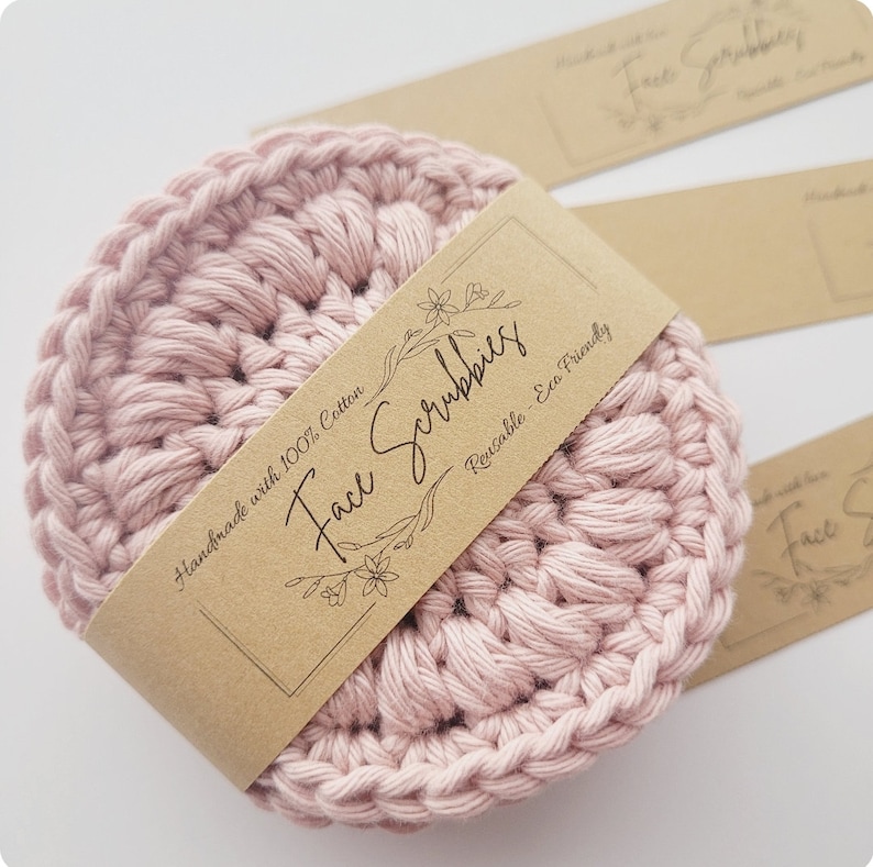 May include: Pink crocheted face scrubbies made with 100% cotton. The scrubbies are reusable and eco-friendly. The label reads "Handmade with 100% Cotton Face Scrubbies Reusable - Eco Friendly".