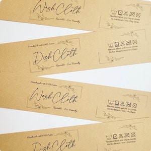 May include: Four brown paper tags with black text and floral designs. Each tag says "Wash Cloth" or "Dish Cloth" and includes the text "Handmade with 100% Cotton" and "Reusable - Eco Friendly". Each tag also includes a set of laundry care symbols indicating machine wash and dry on gentle, do not bleach, iron, or dry clean.