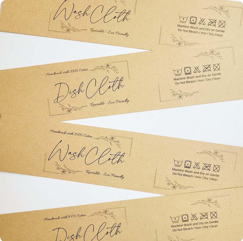 May include: Four brown paper tags with black text and floral designs. Each tag says "Wash Cloth" or "Dish Cloth" and includes the text "Handmade with 100% Cotton" and "Reusable - Eco Friendly". Each tag also includes a set of laundry care symbols indicating machine wash and dry on gentle, do not bleach, iron, or dry clean.