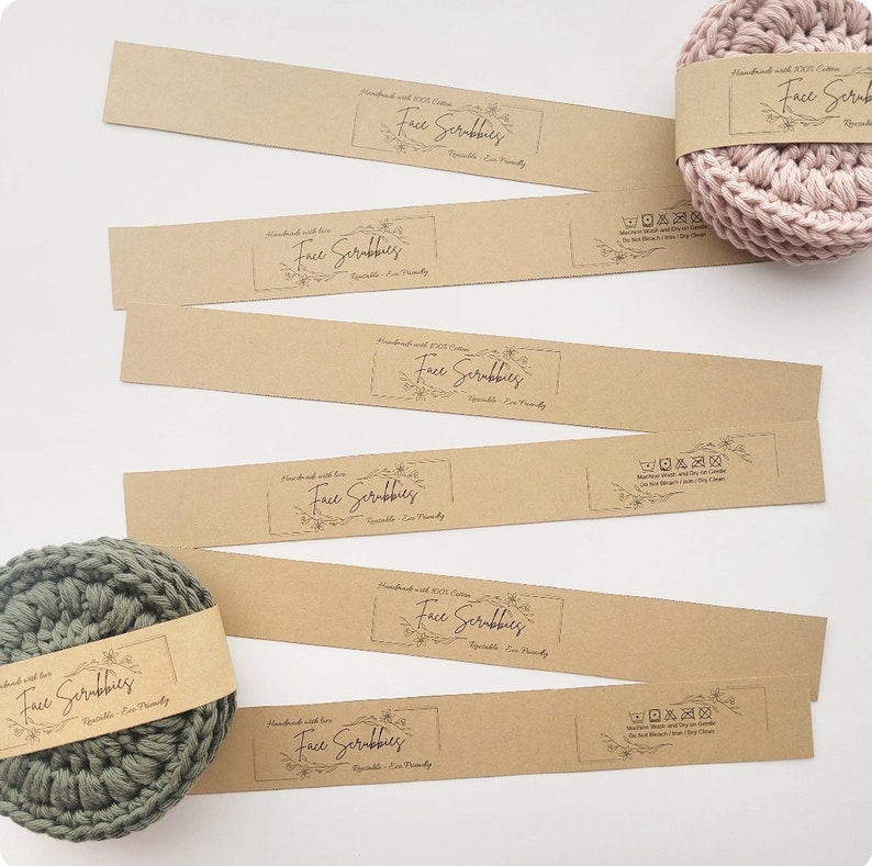 May include: Six brown paper labels with the text "Face Scrubbies" printed on them. The labels are handmade with 100% cotton and are reusable and eco-friendly. There are also care instructions printed on the labels. Two crocheted face scrubbies are shown, one in green and one in pink.