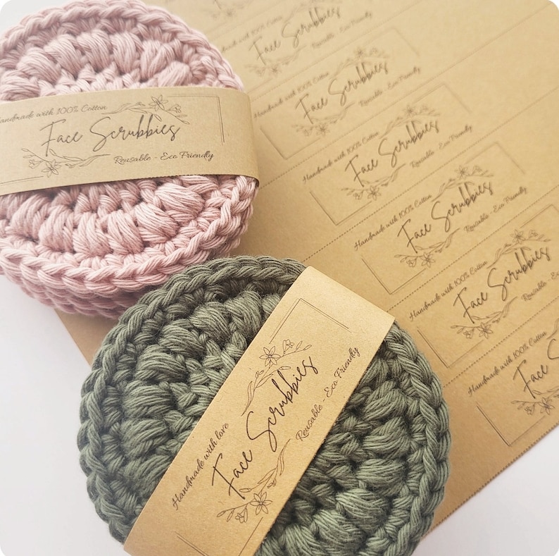 May include: Two handmade crocheted face scrubbies, one in pink and one in green, with brown paper labels that say "Handmade with 100% Cotton Face Scrubbies Reusable - Eco Friendly".