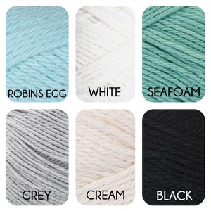 May include: Six skeins of yarn in different colours: robin's egg blue, white, seafoam green, grey, cream, and black.