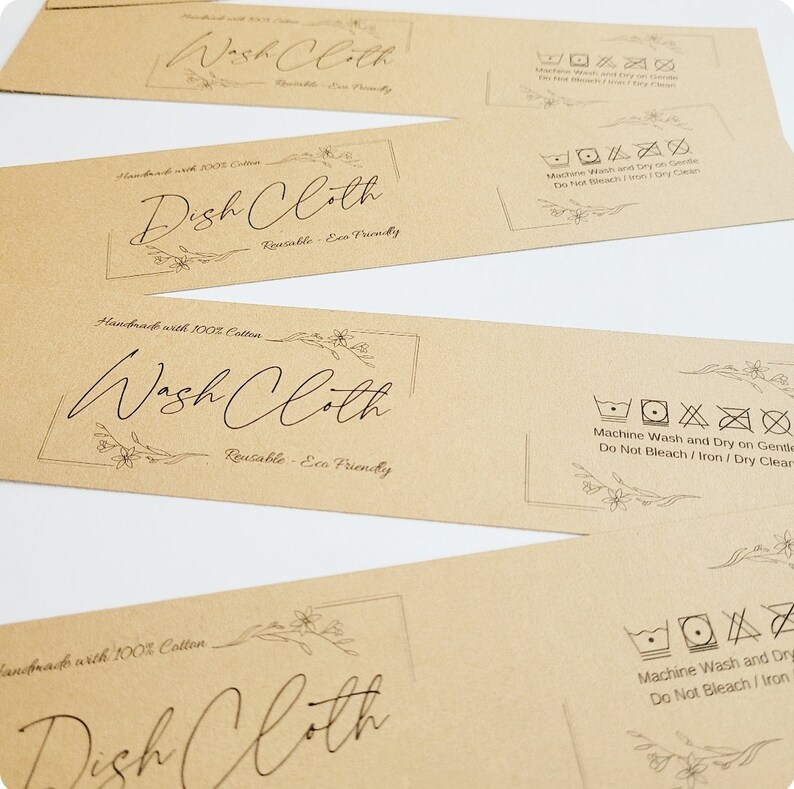May include: Four brown paper tags with black text and floral designs. The tags are for washcloths and dishcloths. The text on the tags reads "Handmade with 100% Cotton", "Wash Cloth", "Reusable - Eco Friendly", "Dish Cloth", and "Machine Wash and Dry on Gentle, Do Not Bleach/Iron/Dry Clean".
