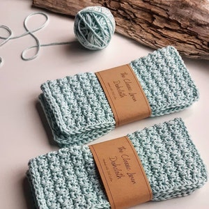 May include: Two light blue linen dishcloths with brown labels that read "The Classic Linen Dishcloth Handmade with 100% Cotton".