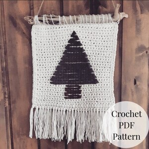 May include: Crochet pattern PDF for a white crocheted wall hanging with a black tree design and fringe.