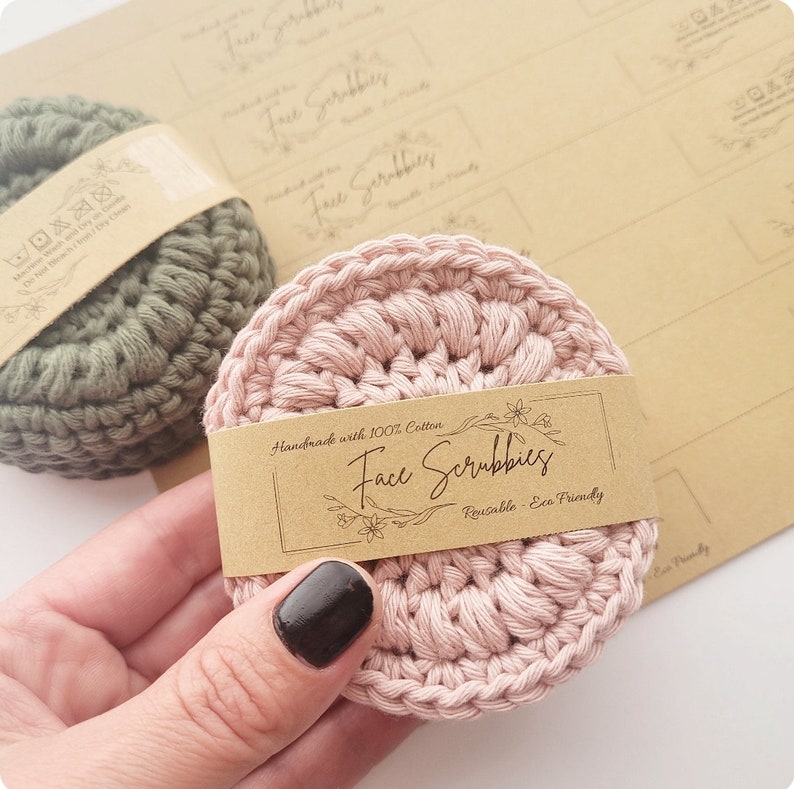 May include: Two crocheted face scrubbies, one pink and one green, with a brown label that reads "Handmade with 100% Cotton Face Scrubbies Reusable - Eco Friendly".