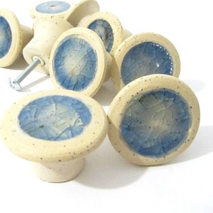 Peut inclure: Ensemble de boutons de meubles en céramique. Chaque bouton présente une base blanc cassé mouchetée avec un centre circulaire émaillé bleu. Une vis métallique est fixée à l'un des boutons. Pour meubles et décoration intérieure.