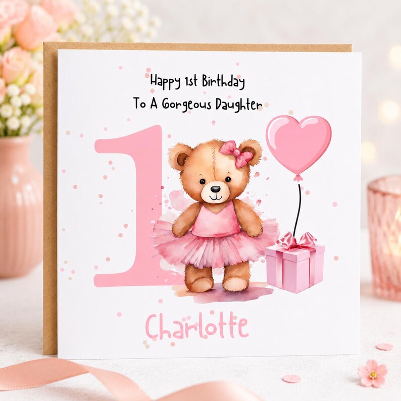 May include: A square greeting card featuring a large pink number one, a brown teddy bear wearing a pink tutu and bow, a pink heart-shaped balloon, and a pink gift box. The text reads Happy 1st Birthday To A Gorgeous Daughter and Charlotte.