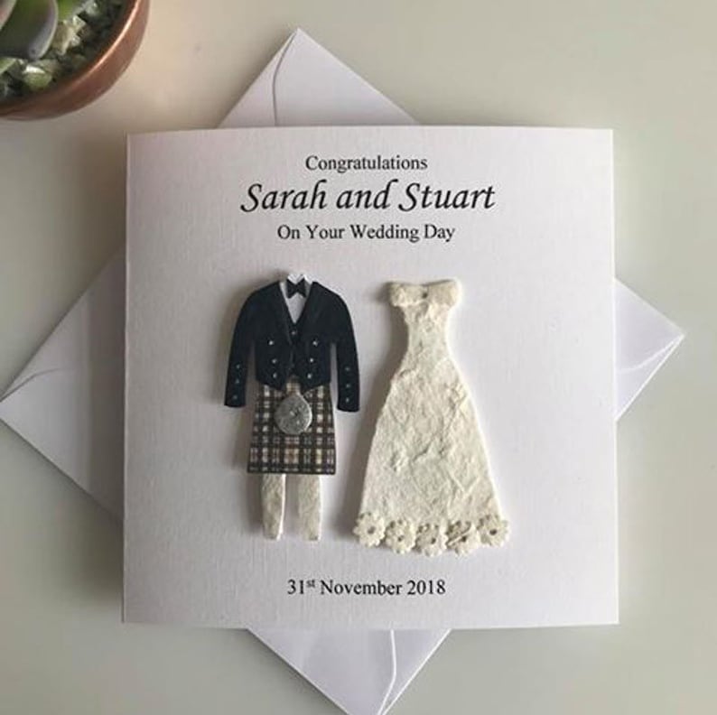 K&ouml;nnte beinhalten: Eine wei&szlig;e Karte mit einer Schwarzwei&szlig;illustration eines Brautpaares. Der Br&auml;utigam tr&auml;gt einen Kilt und die Braut ein wei&szlig;es Kleid. Der Text auf der Karte lautet "Herzlichen Gl&uuml;ckwunsch Sarah und Stuart Zu Eurem Hochzeitstag 31. November 2018".