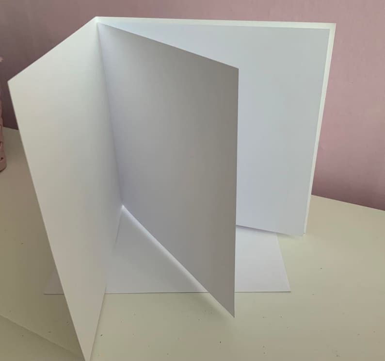 May include: A white card folded in half, with the inside of the card facing the camera. The card is blank.