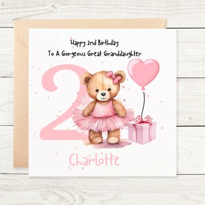 May include: A square greeting card featuring a brown teddy bear wearing a pink tutu and bow. The card displays the text Happy 2nd Birthday To A Gorgeous Great Granddaughter and the name Charlotte. A large pink number 2, a heart balloon, and a gift box.
