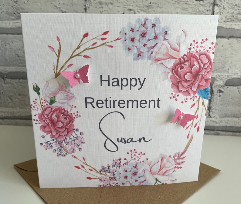 Pu&ograve; includere: Un biglietto bianco con un disegno floreale e il testo "Happy Retirement Susan".
