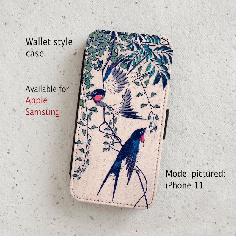 May include: A wallet style phone case with a floral design featuring two blue and white birds perched on branches. The case is available for Apple and Samsung phones. Model pictured: iPhone 11.