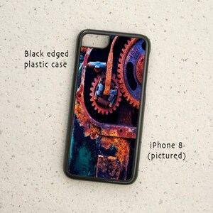 May include: A black-edged plastic phone case with a rusty metal gear design. The case is for an iPhone 8.
