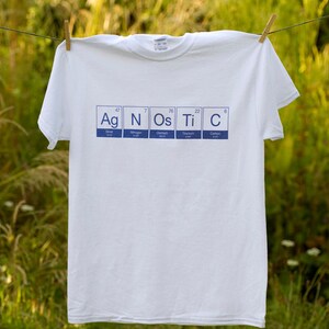 May include: White t-shirt with a blue graphic of the periodic table elements Ag, N, Os, Ti, and C.