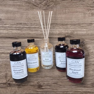 May include: Five glass reed diffuser bottles with black caps and white labels. Scents include Mahogany Teakwood, Lemon Grass, Asian Sandalwood, Patchouli Amber, and MacIntosh Apple. The Asian Sandalwood bottle contains reeds.