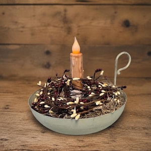 May include: A rustic, light blue metal candle holder with a handle, filled with decorative berry branches and a lit, faux candle. The candle holder sits on a wooden surface, creating a warm, inviting ambiance.
