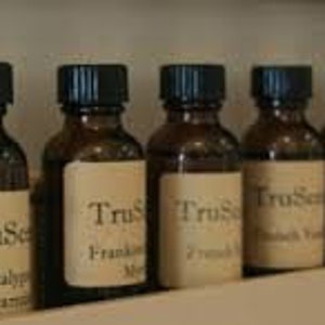 Puede incluir: Una fila de diez peque&ntilde;os frascos de vidrio marr&oacute;n con tapas negras. Cada frasco tiene una etiqueta blanca con el texto "TruScent" y el nombre de un aceite esencial diferente. Los aceites incluyen lavanda inglesa, eucalipto menta, incienso mirra, lim&oacute;n y eucalipto, pachul&iacute;, lavanda inglesa, &aacute;rbol de t&eacute;, menta y eucalipto.