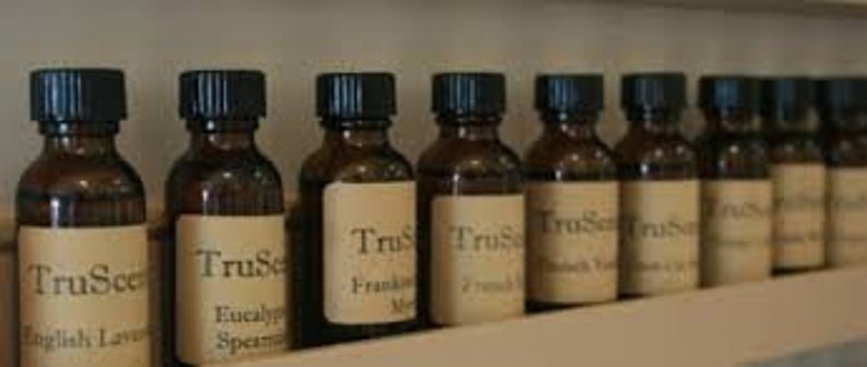 Puede incluir: Una fila de diez peque&ntilde;os frascos de vidrio marr&oacute;n con tapas negras. Cada frasco tiene una etiqueta blanca con el texto "TruScent" y el nombre de un aceite esencial diferente. Los aceites incluyen lavanda inglesa, eucalipto menta, incienso mirra, lim&oacute;n y eucalipto, pachul&iacute;, lavanda inglesa, &aacute;rbol de t&eacute;, menta y eucalipto.