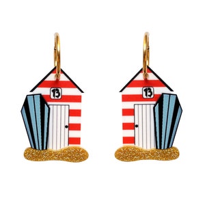 May include: A pair of red and white striped beach hut earrings with blue and white striped beach umbrellas. The earrings have gold hoops and glitter accents.