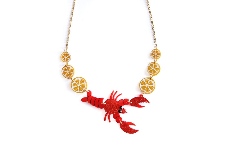 May include: A red lobster charm necklace with gold chain and lemon slice charms.