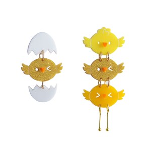 May include: A pair of dangle earrings featuring a yellow chick emerging from a white eggshell. The chick is decorated with glitter and has a small orange beak. The other earring features three yellow chicks stacked on top of each other, with the top chick having a solid yellow color, the middle chick having glitter, and the bottom chick having a solid yellow color.