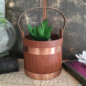 May include: A white ceramic mug with a black handle and the text "But First, Coffee" in a bold, black font. The mug is set against a neutral background, highlighting its simple design.