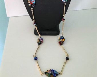 May include: A gold chain necklace with colorful glass beads. The beads are oval shaped and have a mosaic pattern. The necklace is approximately 24 inches long.