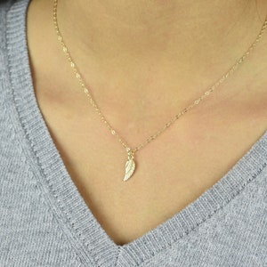 May include: A delicate gold chain necklace with a small, detailed gold wing pendant.