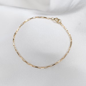 May include: A gold chain bracelet with a box chain design. The bracelet is made of solid gold and has a lobster clasp closure.