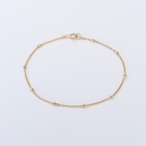 May include: A delicate gold chain bracelet with small round beads.