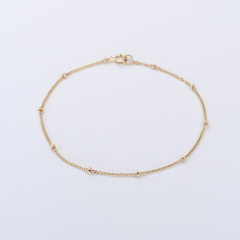 May include: A delicate gold chain bracelet with small round beads.