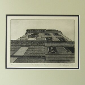 May include: A black and white etching of a building in Rome, Italy. The building is viewed from a low angle, looking up at the facade. The etching is titled "Looking up in Rome" and signed "J. Safranyos 1985".