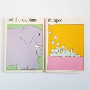 May include: Two vintage children's flashcards. One card features a purple elephant with the text "and the elephant" on a green background. The other card has the word "dumped" with a yellow background and white shapes.