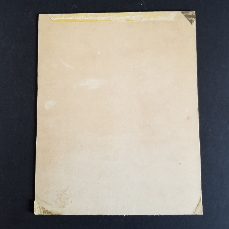May include: A blank, off-white card with a light brown border. The card has a piece of tape on the top edge.