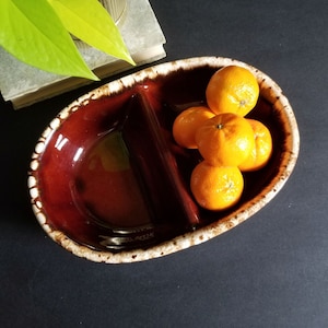 May include: A divided ceramic serving dish with a brown glaze and white speckles. The dish is filled with orange mandarins.