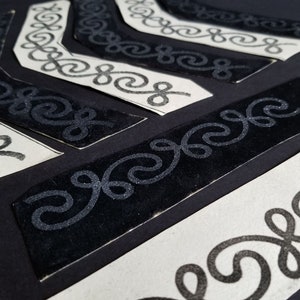 Peut inclure: Gros plan sur plusieurs galons en velours noir avec un motif en spirale. Les galons sont sur un fond blanc.