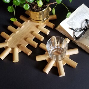 May include: Two wooden coasters, one shaped like a star and the other a long oval, with rounded edges. The star-shaped coaster has a glass on top.