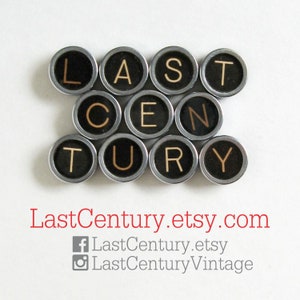 Pu&ograve; includere: Disposizione di tasti di macchina da scrivere vintage che compongono la scritta "LAST CENTURY", con sfondo nero e lettere dorate. I tasti sono disposti a cerchio. Il testo "LastCentury.etsy.com" &egrave; visualizzato in rosso.