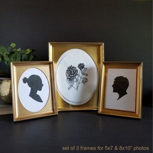 May include: Set of three gold picture frames with a black and white silhouette of a person in each frame. The frames are for 5x7 and 8x10 inch photos.