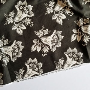 Op de afbeelding: Zwart-witte stof met een herhalend patroon van gestileerde bloemen. De stof is gelabeld "Windham Fabrics  *Nouveau c. 1910 by Nancy Gere Pattern #25928"