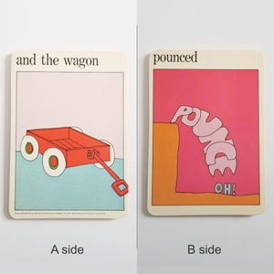 an image showing both sides of the same rectangular card. Side A has an illustration of a red children's wagon on a blue & pink background. The card has the text 'and the wagon' at the top. Side B has a pink and orange illustration of the word 'pounce' falling off a cliff with the word 'OH!' below it. The word 'pounced' is at the top of the image.